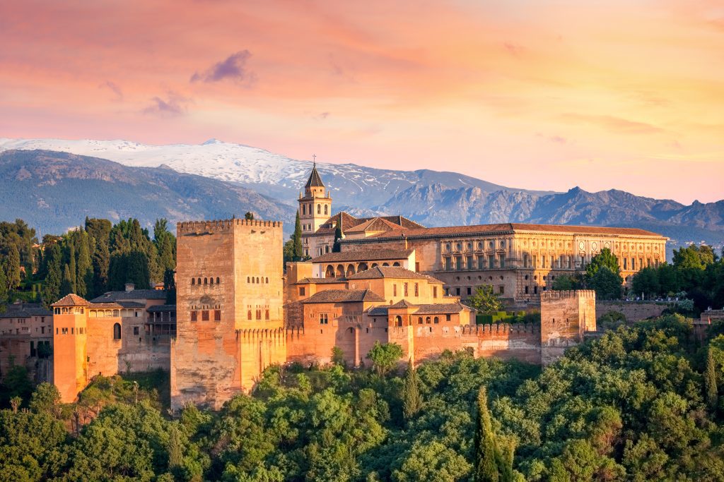 Panorámica de la Alhambra desde un mirador al atardecer con Sierra Nevada de fondo.